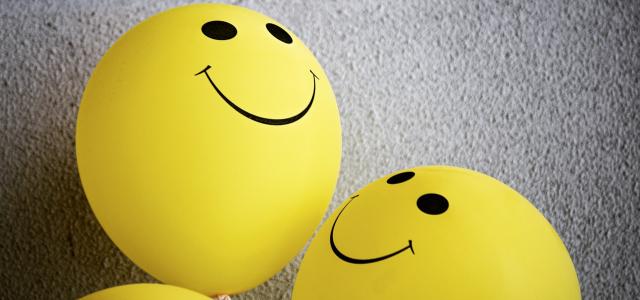 Two yellow balloons with smiley faces on them